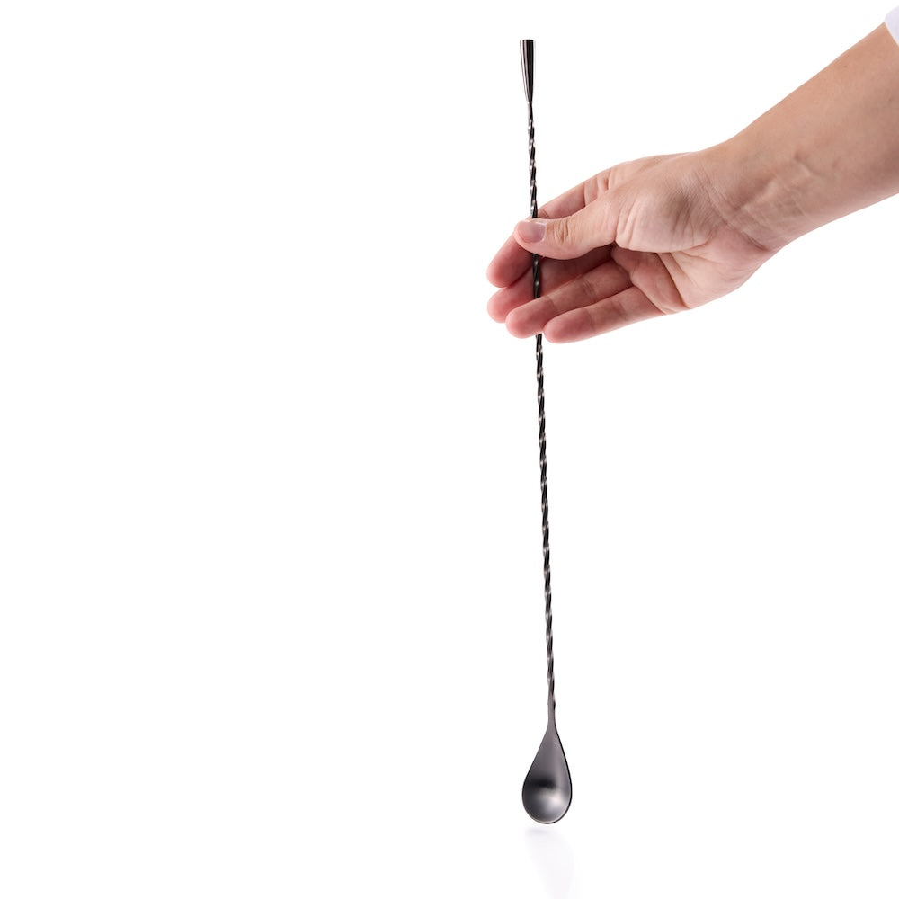 Cocktail bar spoon held by a hand on a white background