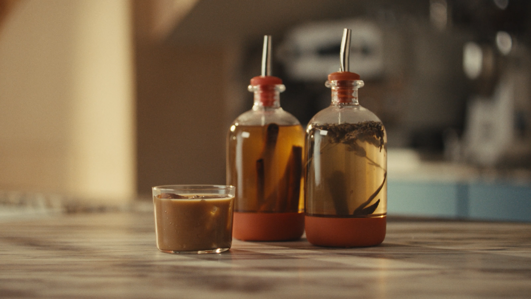 Two chubby bottles with syrup infusions with a latte on the counter