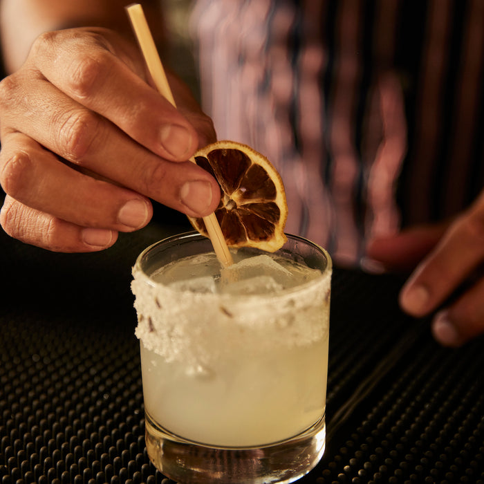 Craft cocktail styled with lemon cocktail garnish plant-based straw and lavender lemonade rimming salt