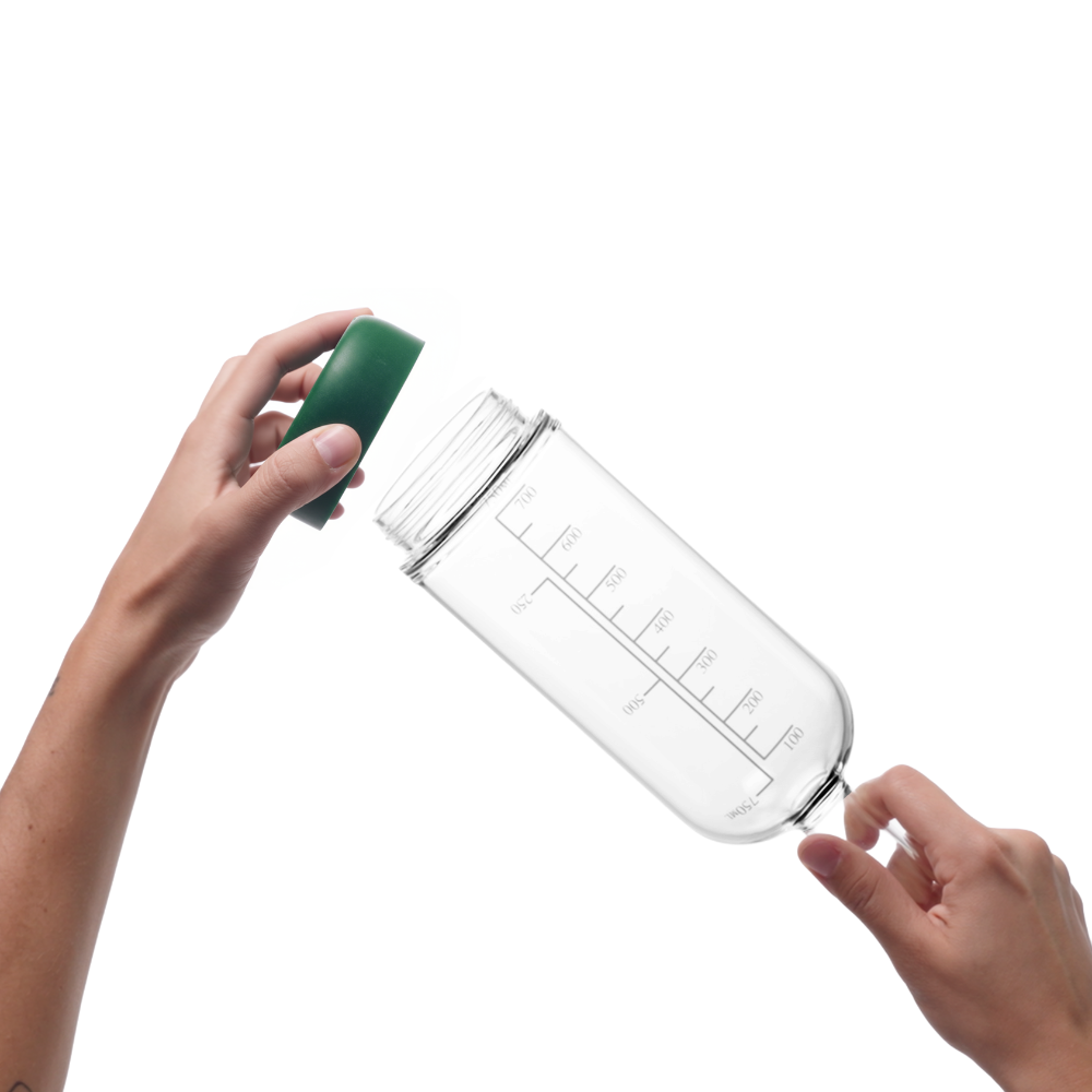 Glass pre-batch bottle with Basil removable base being held by a person on a white background