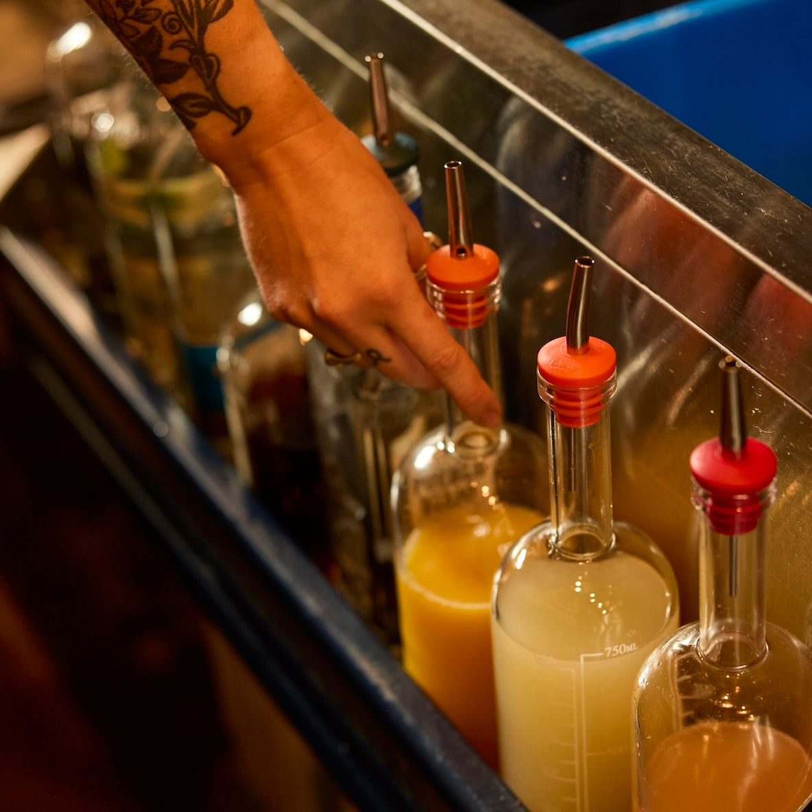 Pour spouts and batch bottles lining a craft bar well