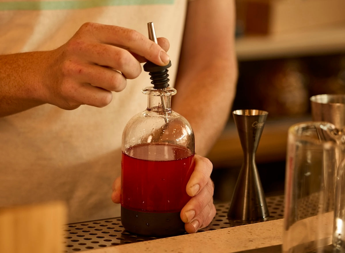 Pour spout being placed in infusion bottle at a craft bar