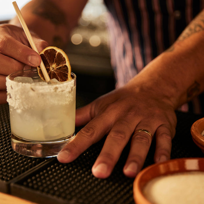Bartender garnishing craft cocktail with bar supplies