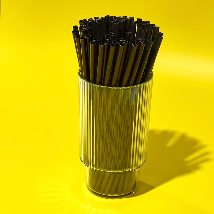 Tall black plant-based agave straws for cocktails stacked in a glass