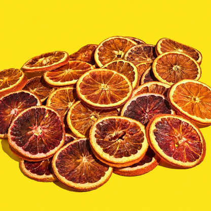 A pile of dried blood orange citrus slices arranged on a bright yellow background.