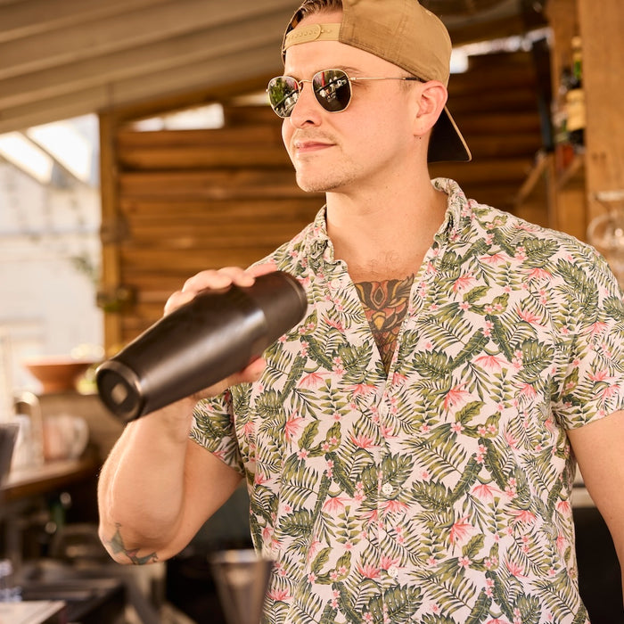 Craft bartender wearing sunglasses and backwards hat using a boston-style cocktail shaker to make craft cocktails at an outdoor bar