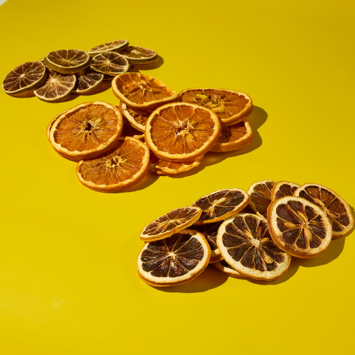 Dehydrated lime wheels, dehydrated orange slices, and dehhydrated lemon wheels in piles