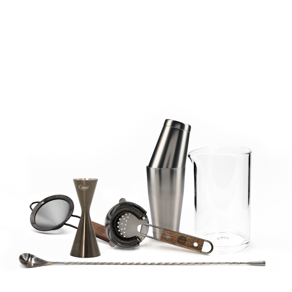 Set of cocktail-making tools including a shaker, jigger, strainer, and spoon on a white background.