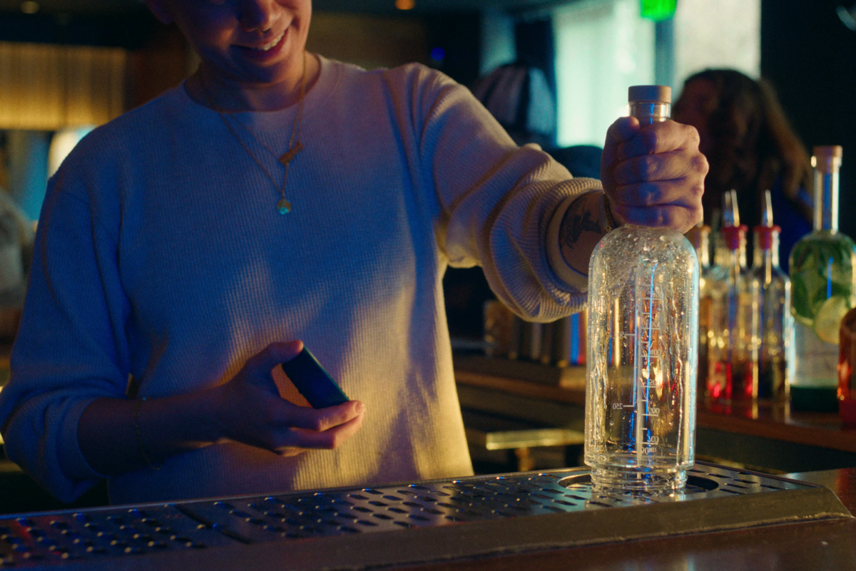 Bartender holding batch bottle with removable base on a scupper for easy cleaning | Crew Bottle