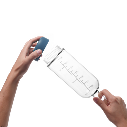 Glass pre-batch bottle with Crew Blue removable base being held by a person on a white background