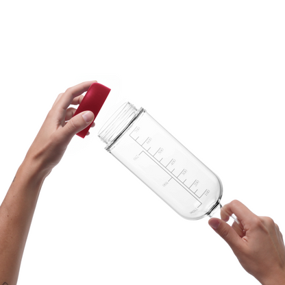 Glass pre-batch bottle with Merlot red removable base being held by a person on a white background