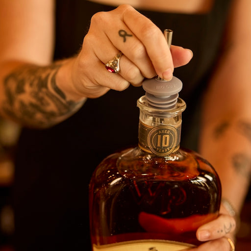 Bartender placing oversized spout onto whiskey bottle