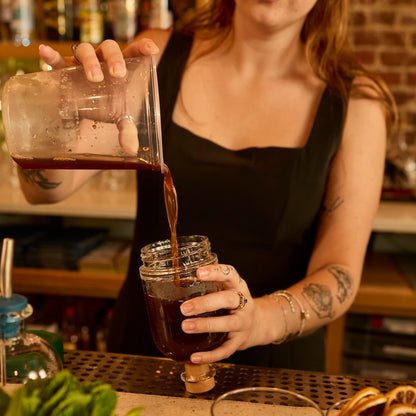 Woman pouring a spirit into a chubby bottle | Crew Barware