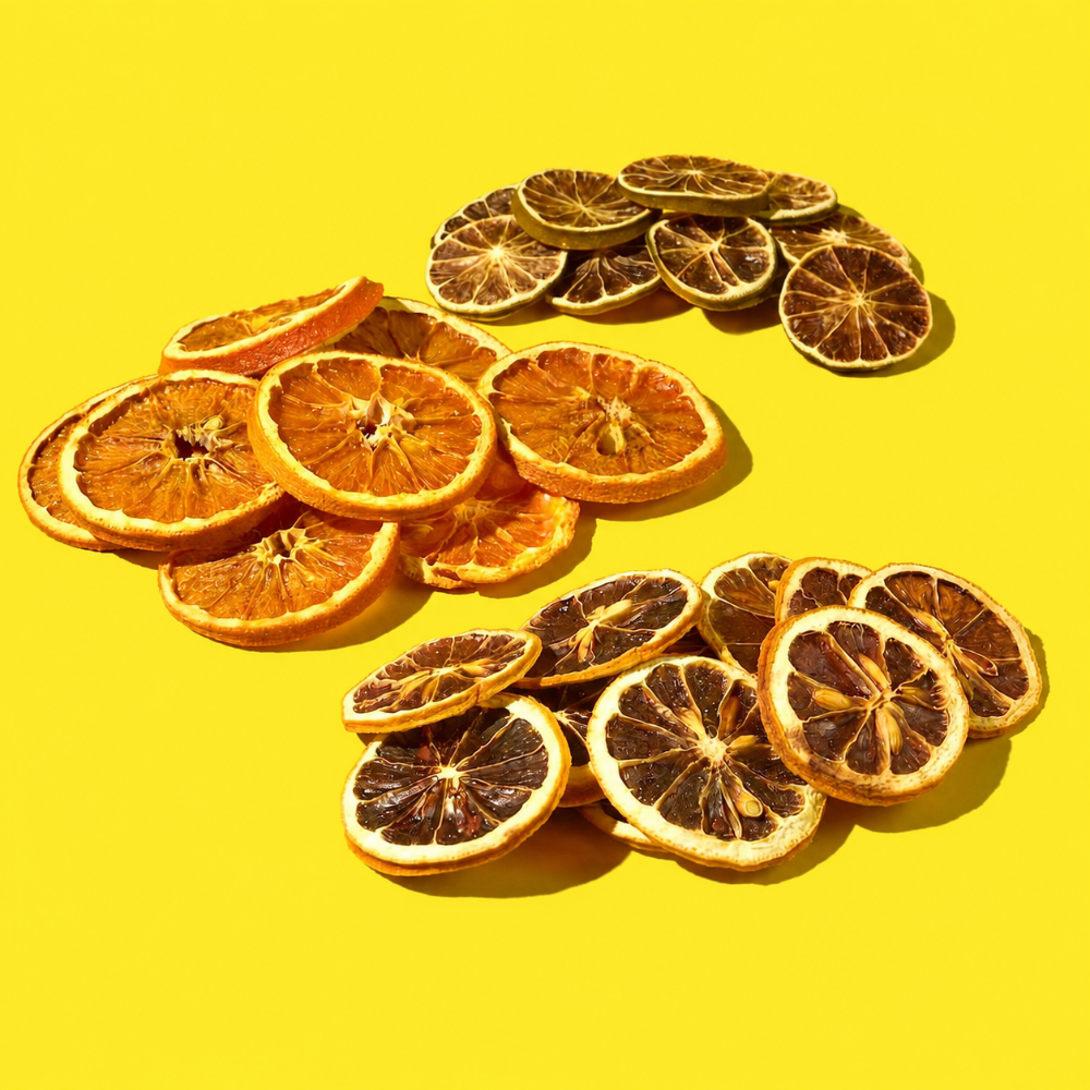 Three piles of dried citrus slices, lemons, oranges, and limes, arranged on a bright yellow background.