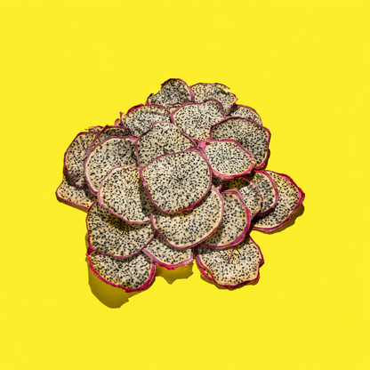 A pile of sliced dragon fruit pieces with white flesh, black seeds, and pink-red skins, arranged on a bright yellow background.