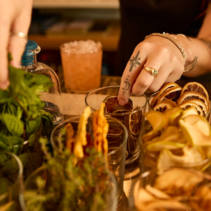 Bartender grabbing dehydrated lime wheels at the garnish station of a craft cocktail bar