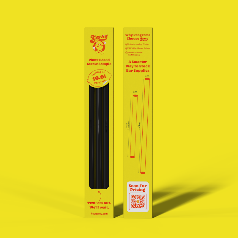 A yellow retail box for a plant-based straw sample stands upright on a solid yellow background. The box shows a black Agave straw sample inside a narrow window and includes printed text, a price callout, dimensions, and a QR code.