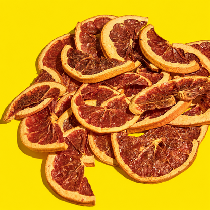Pile of dehydrated grapefruit halves for cocktail garnishes on a yellow background