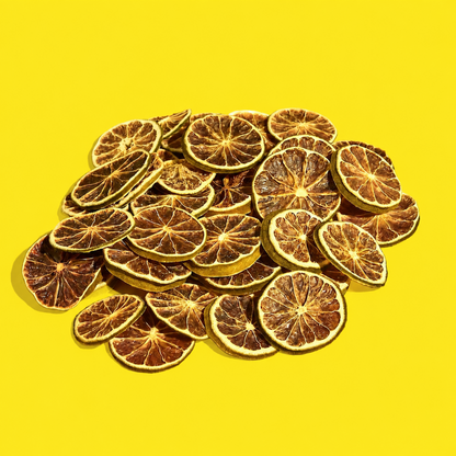 Pile of dehydrated lime wheels for cocktail garnishes on a yellow background