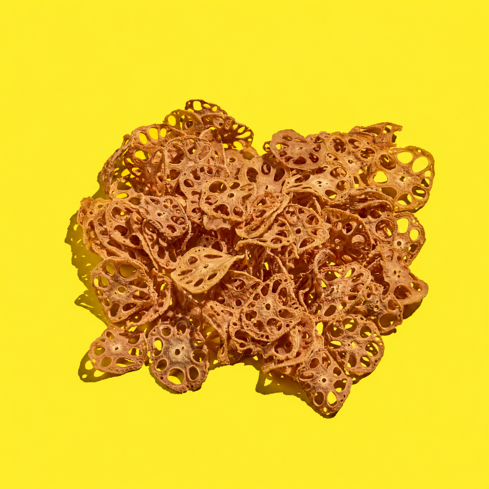 A pile of dehydrated lotus root slices arranged on a solid bright yellow background.