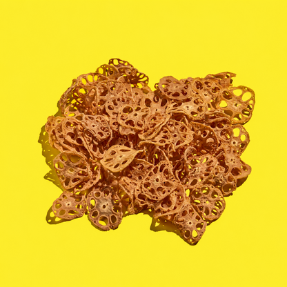 A pile of dehydrated lotus root slices arranged on a solid bright yellow background.