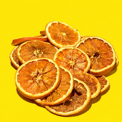 A pile of dried orange slices arranged on a bright yellow background.