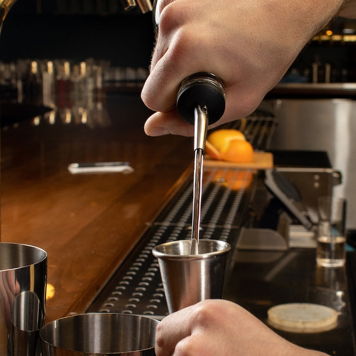 Bartender pouring into bar jigger with pour spout